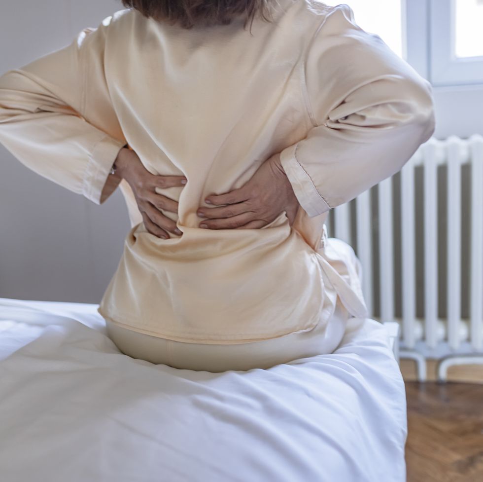 woman feels back pain massaging aching muscles