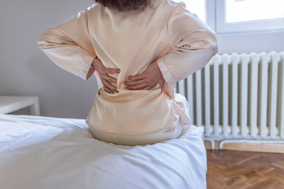 woman feels back pain massaging aching muscles