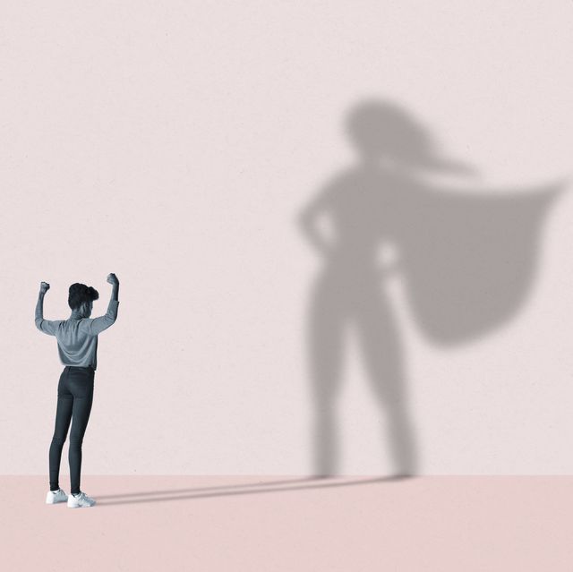 woman flexing muscles in front of superhero shadow