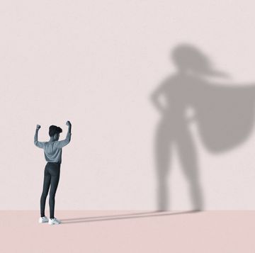 woman flexing muscles in front of superhero shadow
