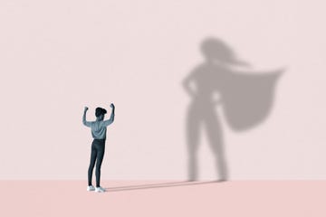 woman flexing muscles in front of superhero shadow