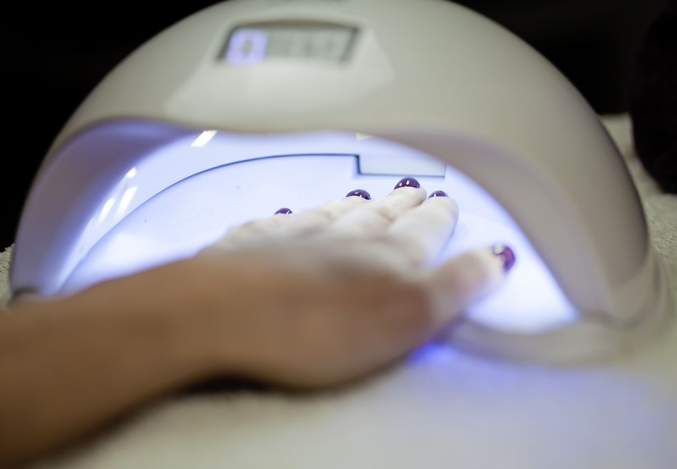 Woman Fliling Nails With UV Lamp in Background.