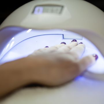 woman fliling nails with uv lamp in background