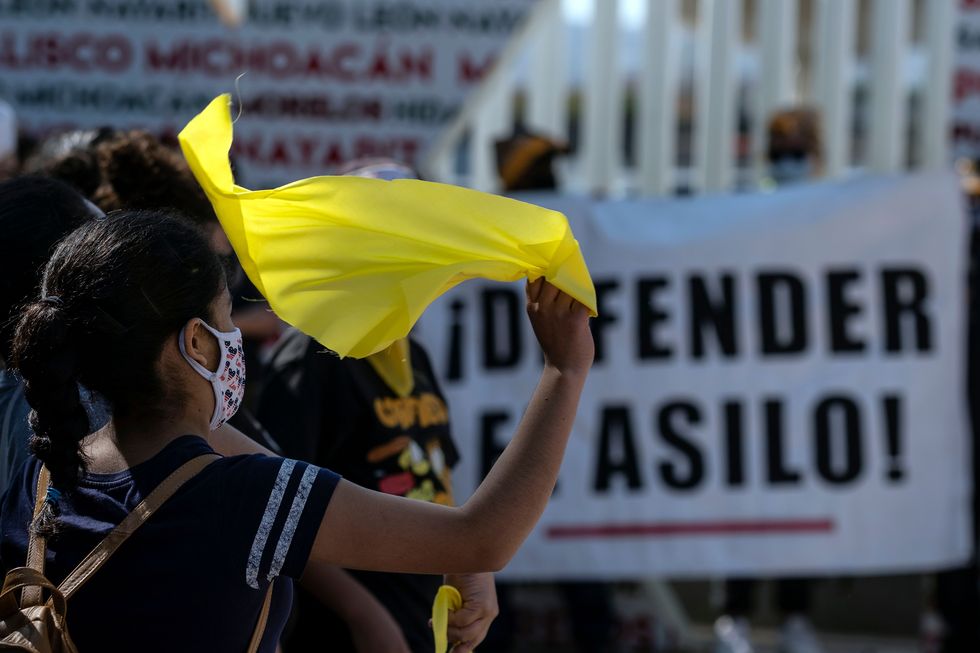 a woman flutters a yellow handkerchief during a protest of migrants and human rights activists against us and mexican migration policies at the san ysidro crossing port, in tijuana, mexico, on the border with the us, on october 21, 2020, amid the covid pandemic