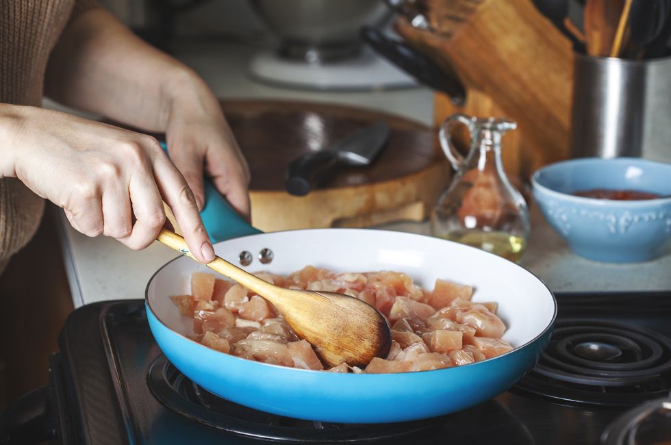 woman frying chicken breast on the skillet