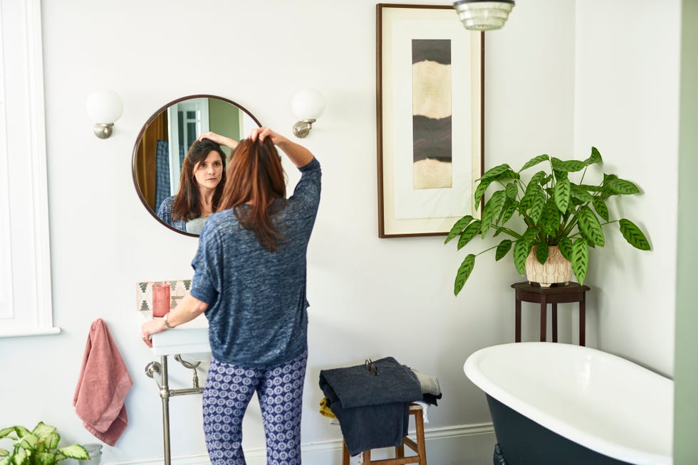 woman getting ready looking in bathroom mirror