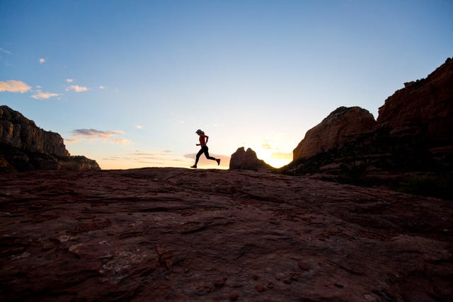 A woman goes for a cross-country trail run at sunset in Sedona, Arizona, USA.