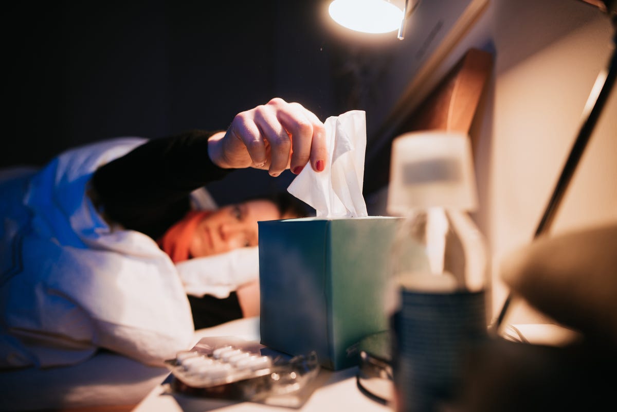 woman grabing tissue paper in bed
