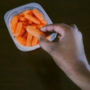 woman grabs baby carrot from container