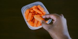 woman grabs baby carrot from container
