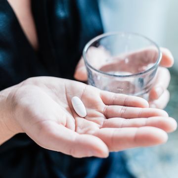 woman hand and pill and glass of water