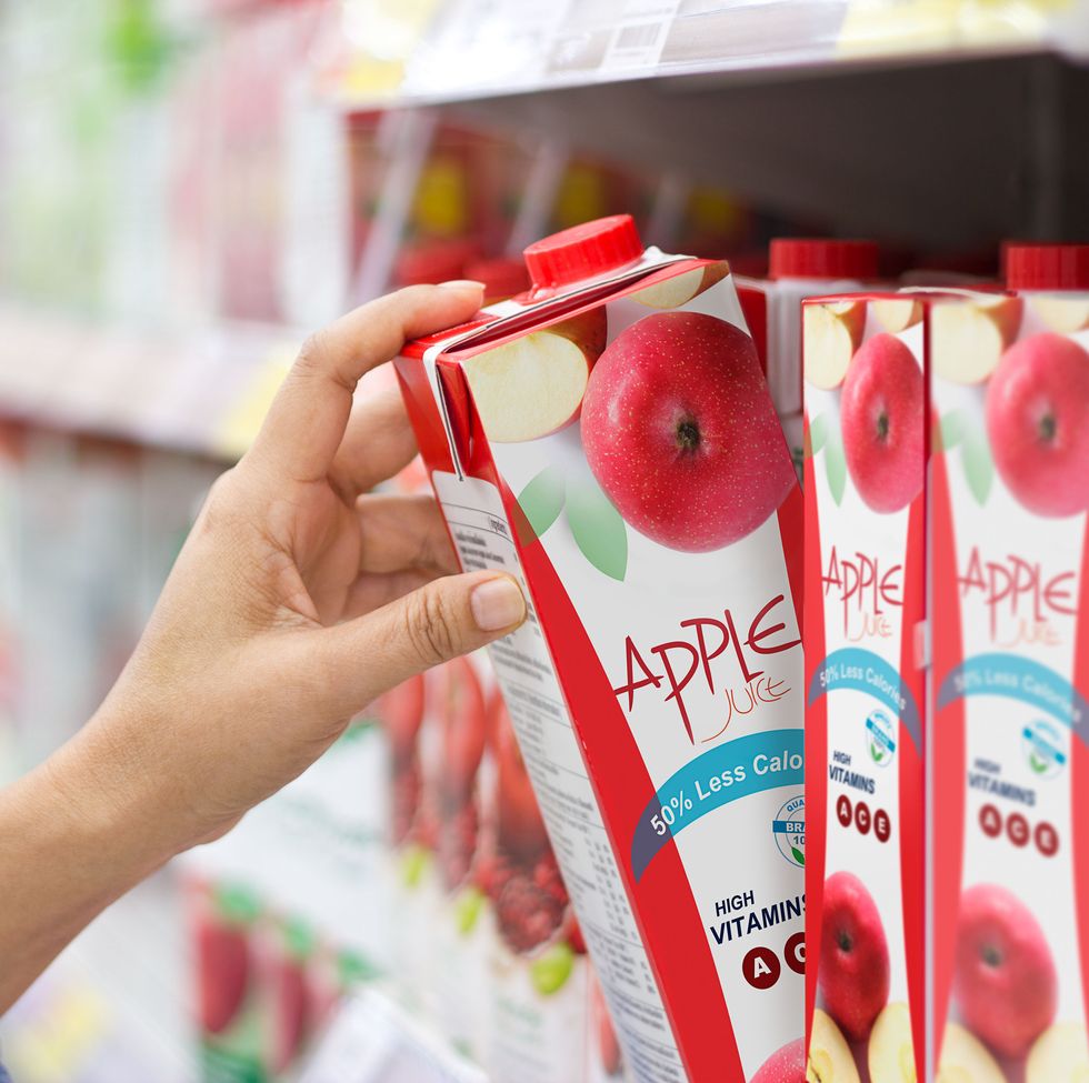 woman hand choosing to buy apple juice on shelves in supermarket
