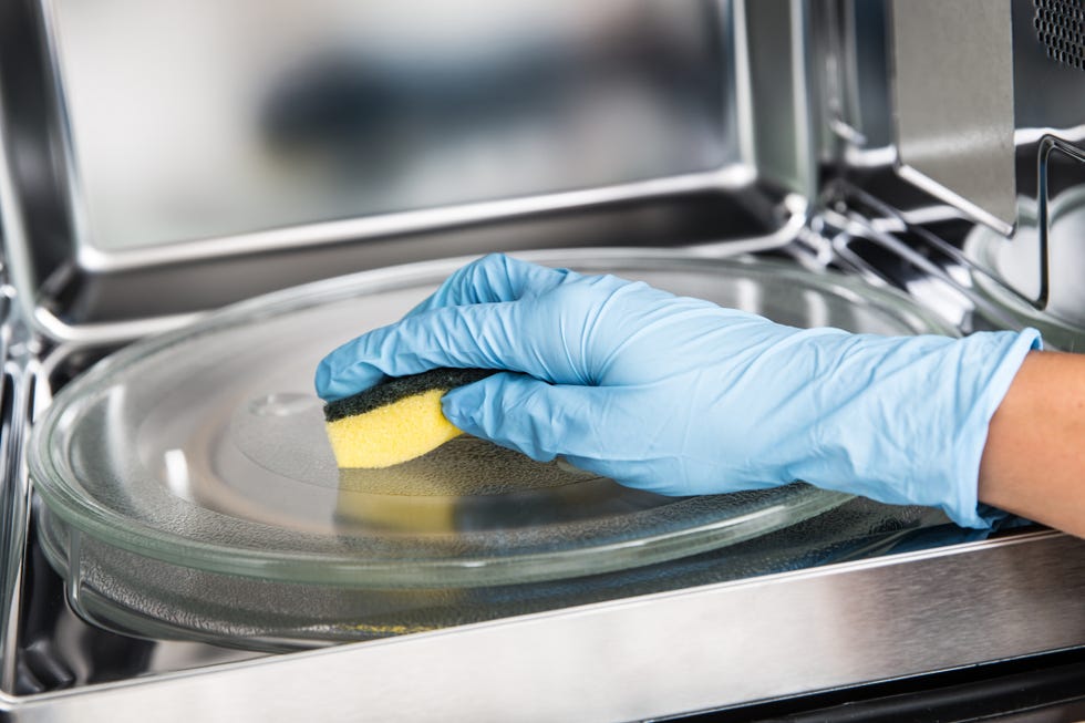 woman hand cleaning microwave oven with sponge