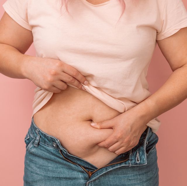 woman hand holding excessive belly fat, overweight concept overweight female wearing a jeans