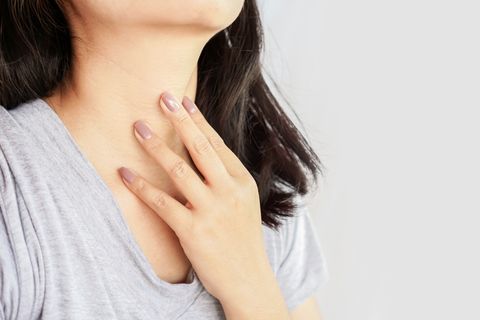woman hand self checking thyroid gland on her neck