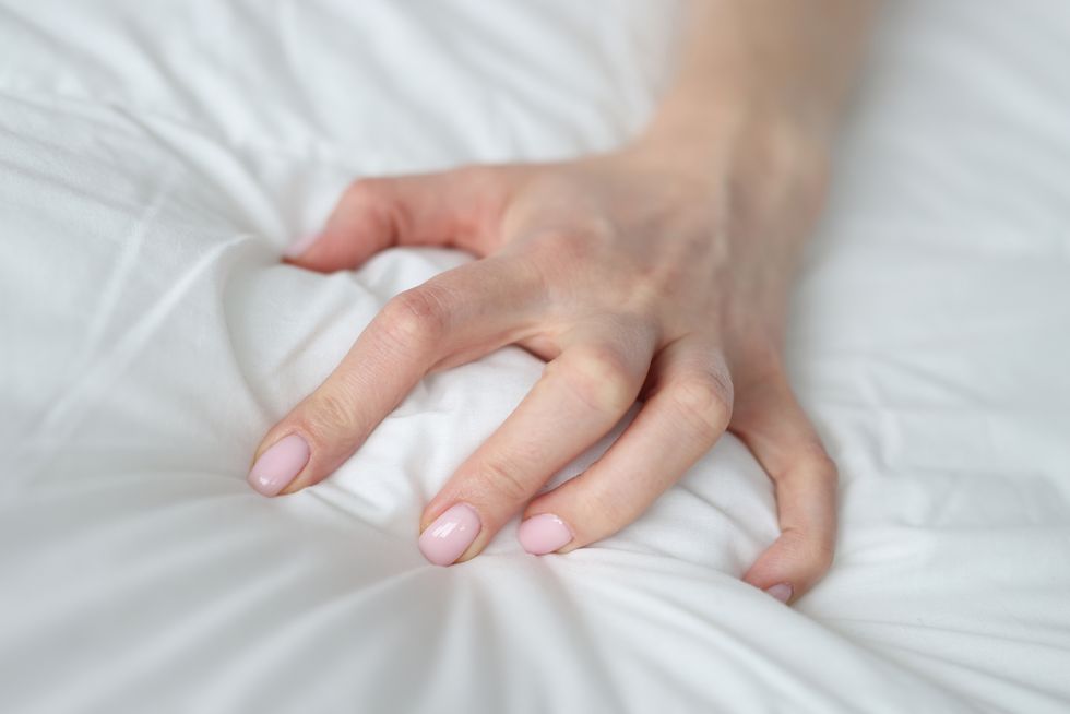 woman hand squeezing white blanket at home closeup
