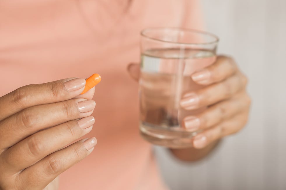 woman hand taking pill and glass of water in hand