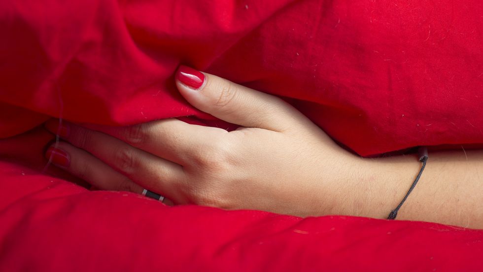 woman hand under a red blanket