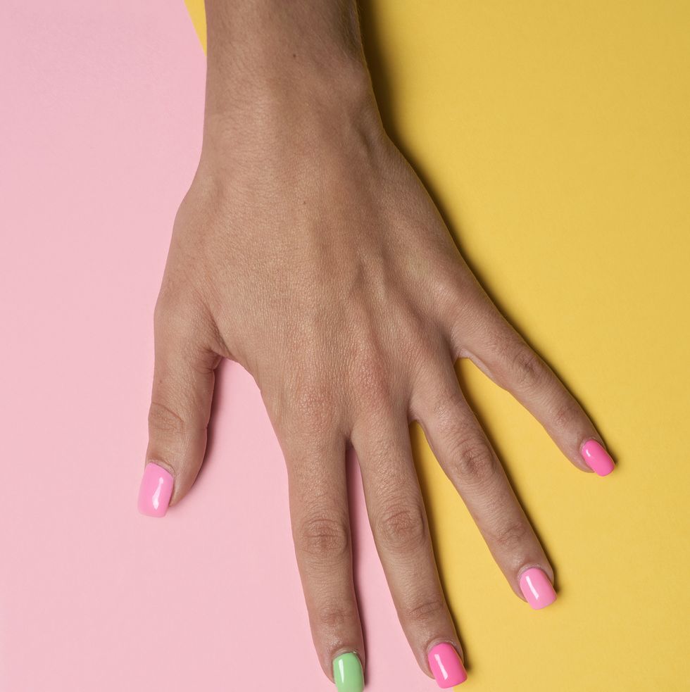 woman hand with her nails painted pink and green