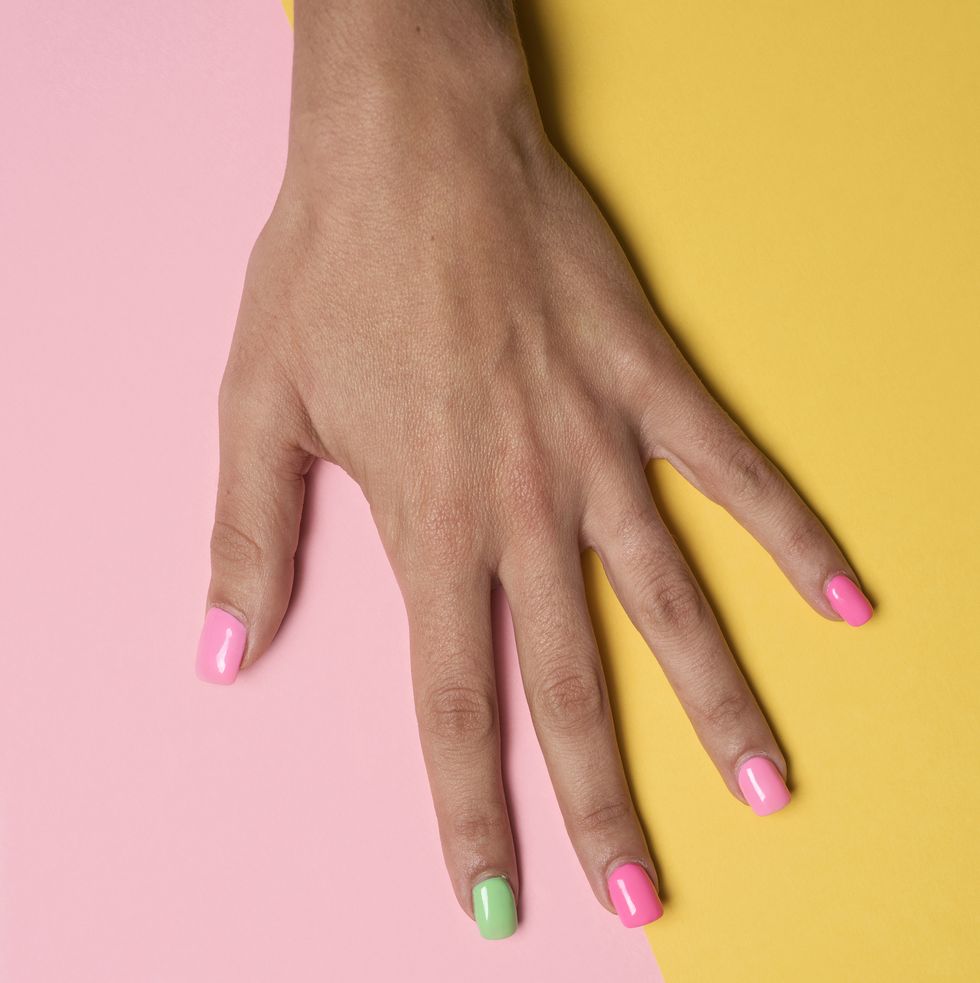 woman hand with her nails painted pink and green