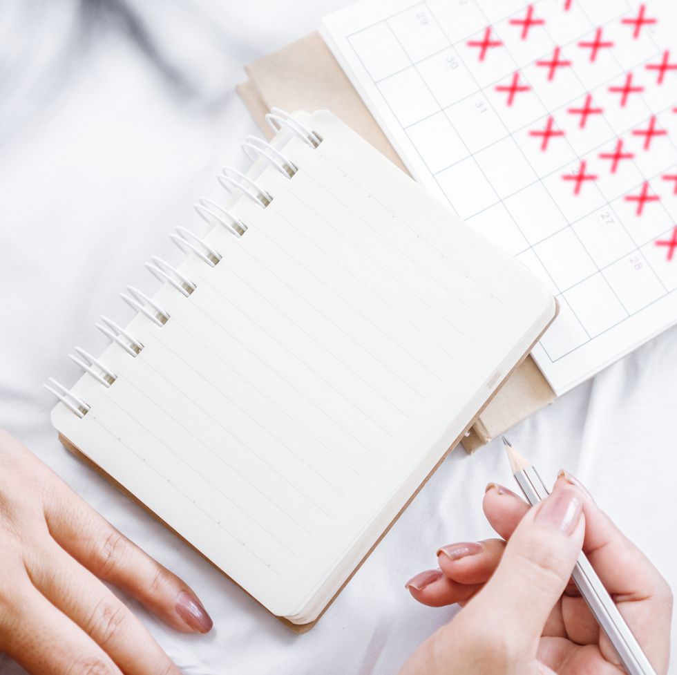 woman hand writing on blank notebook, diary counting date on calendar page ,concept for planning, to do list