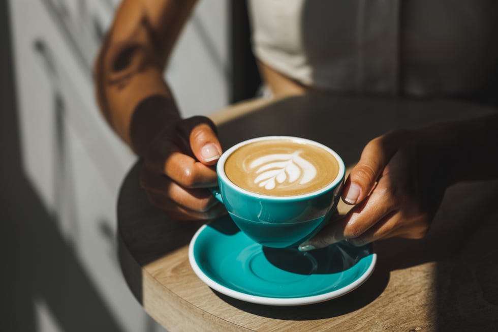 Woman hands holding cup of fresh cappuccino close up. Beautiful natural sun light in cafe woman hands holding cup of fresh cappuccino close up beautiful natural sun light in cafe