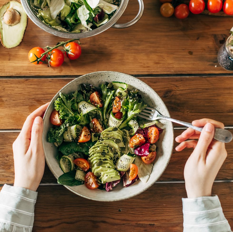 woman hands holding summer salad with raw vegetables cabbage, spinach, radish, parsley, greens in bowl for dinner or lunch. vegan vegetarian healthy food.