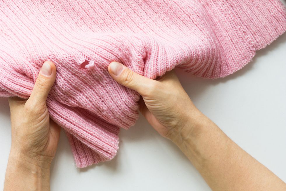woman hands holding knitted thing with hole made by mole
