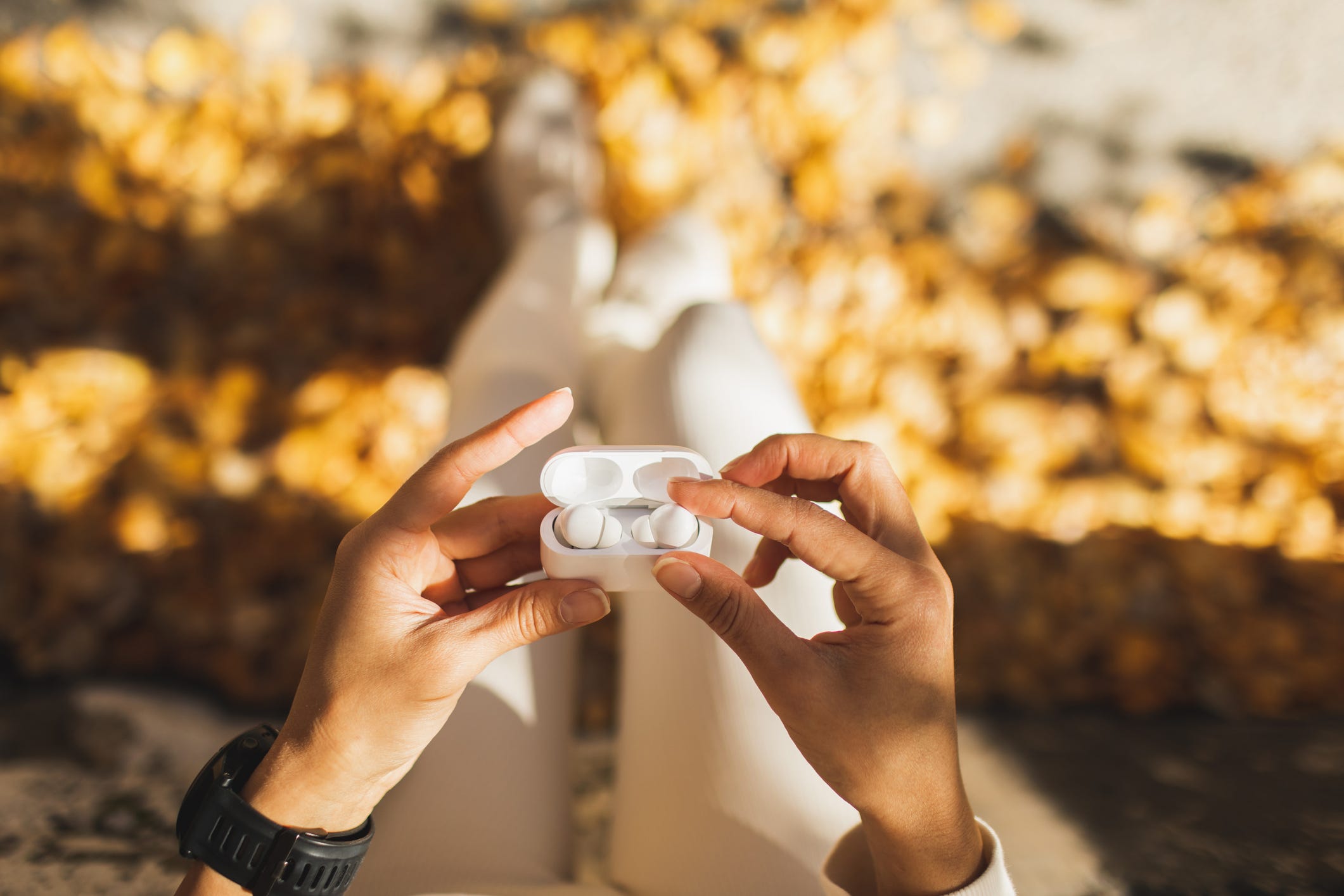woman hands holding wireless pods earphones close up listening music while running