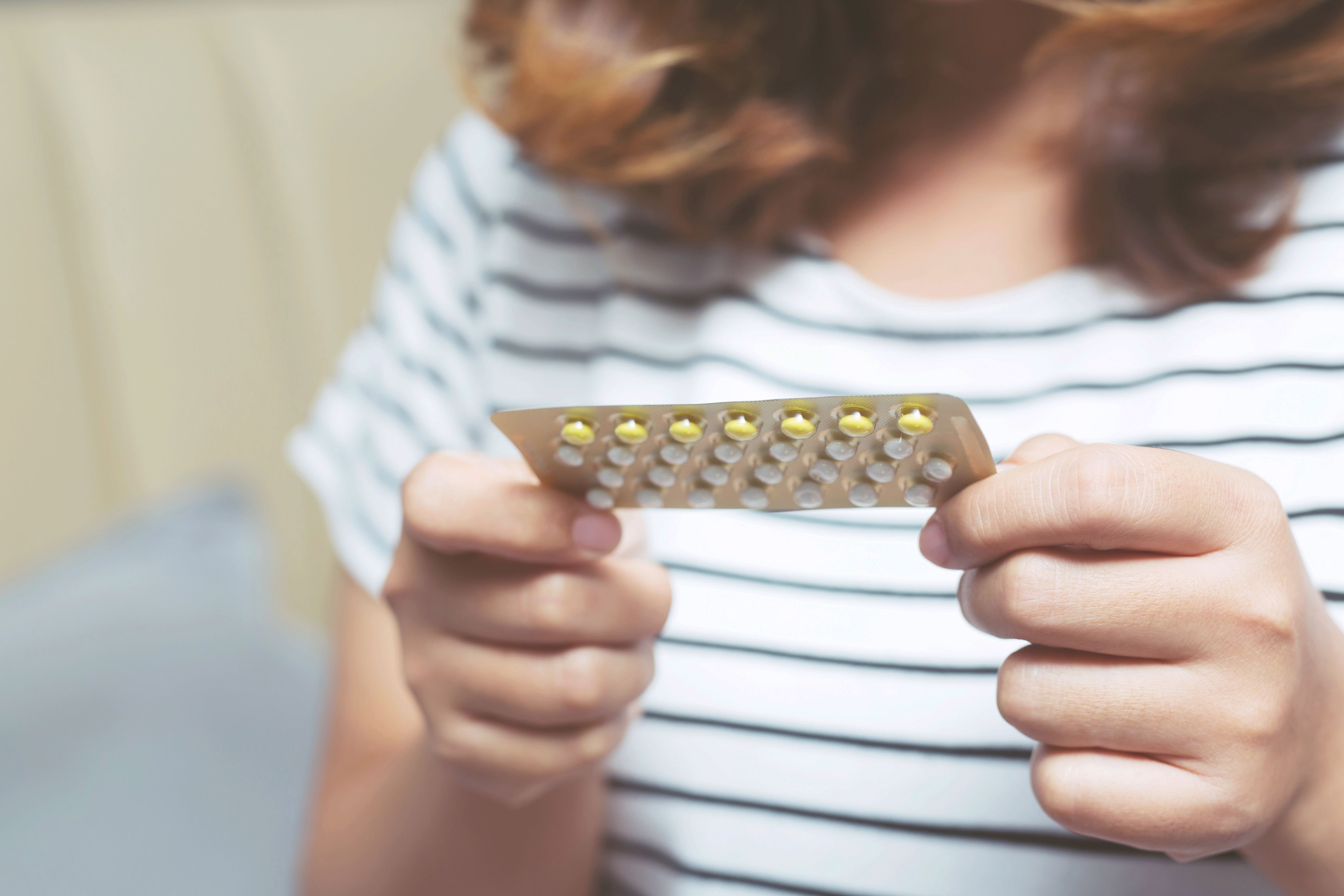 woman hands opening birth control pills in hand on the bed in the bedroom eating contraceptive pill