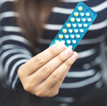 woman hands opening birth control pills in hand eating contraceptive pill
