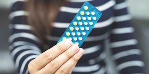 woman hands opening birth control pills in hand eating contraceptive pill