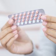 woman hands opening birth control pills in hand