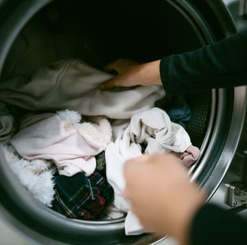 woman hands putting her dirty clothes in the washing machine in a laundromat