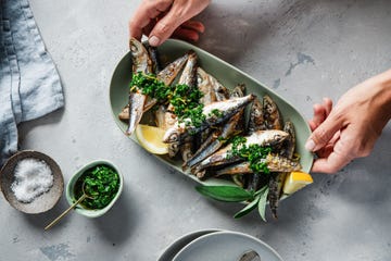 woman hands serving grilled sardines with spices on a table