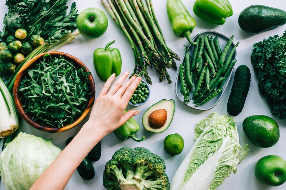 woman hands taking green peas from table with fresh vegetables, healthy nutrition concept