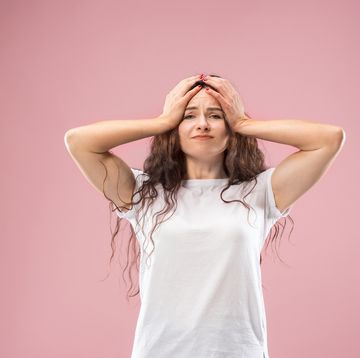 woman having headache isolated over pink background