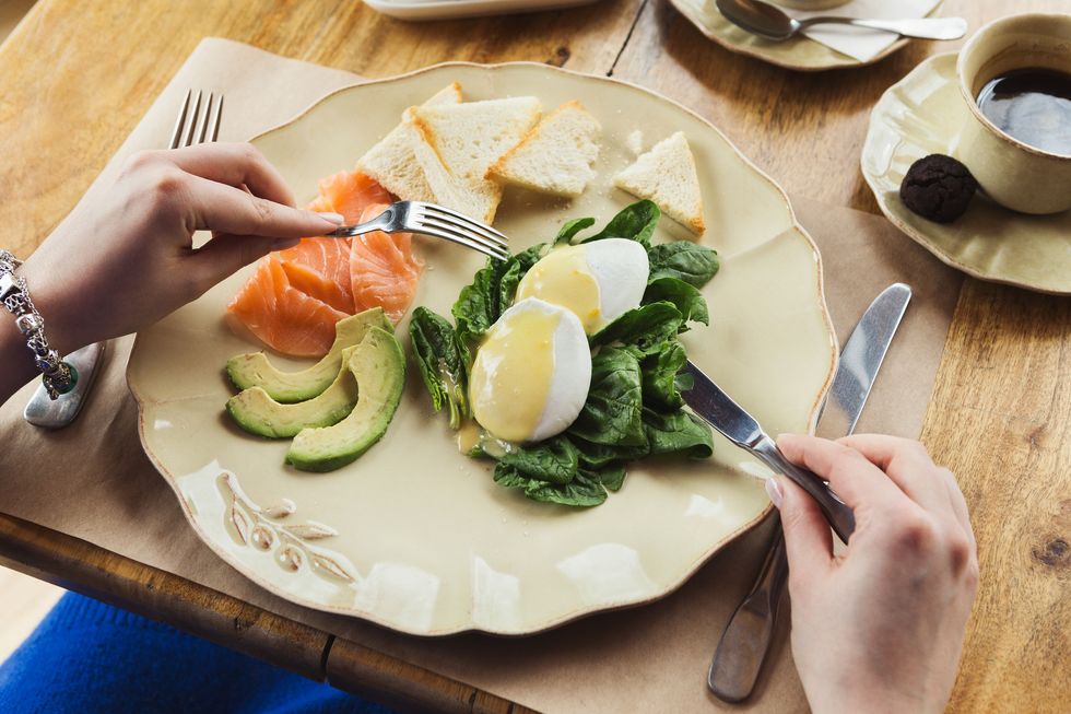 woman having healthy breakfast with poached eggs and smoked salm
