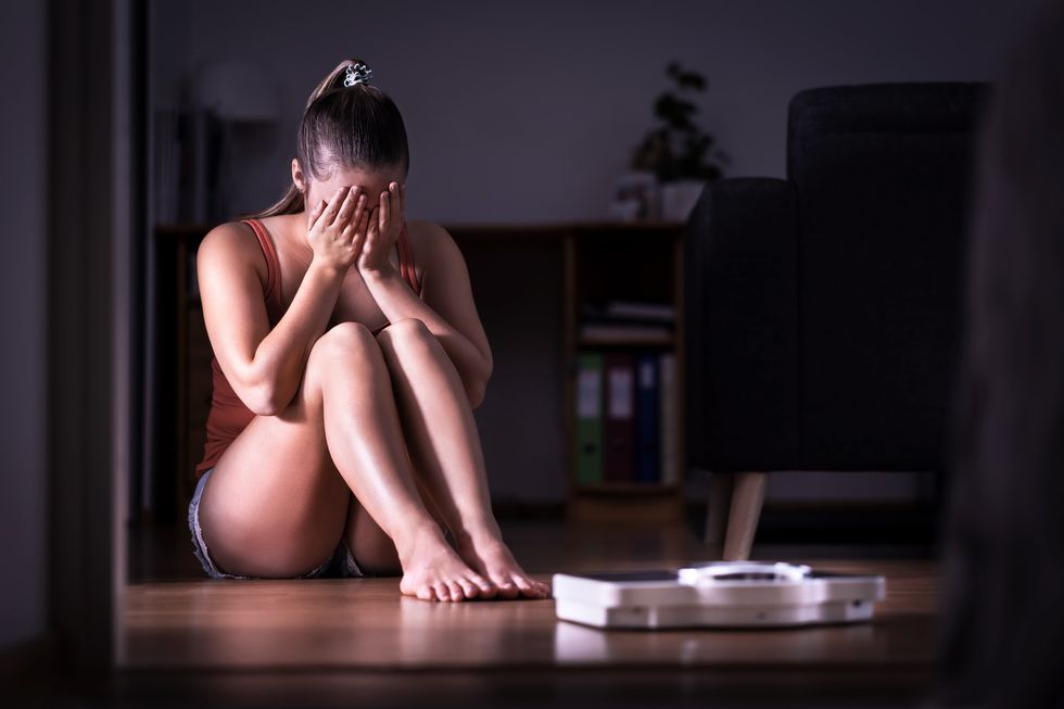 woman having stress about weight loss, diet or gaining weight eating disorder, anorexia or bulimia concept young girl crying and sitting on the floor with scale