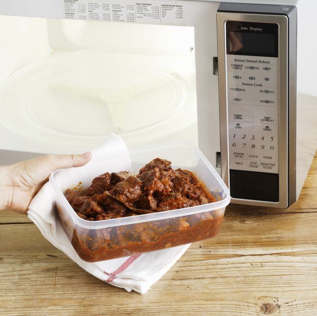 woman heating leftovers in microwave