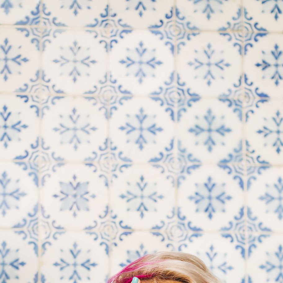 woman hiding half face with one hand against patterned wall