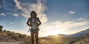 woman hiking at red rock canyon during sunset with backpack