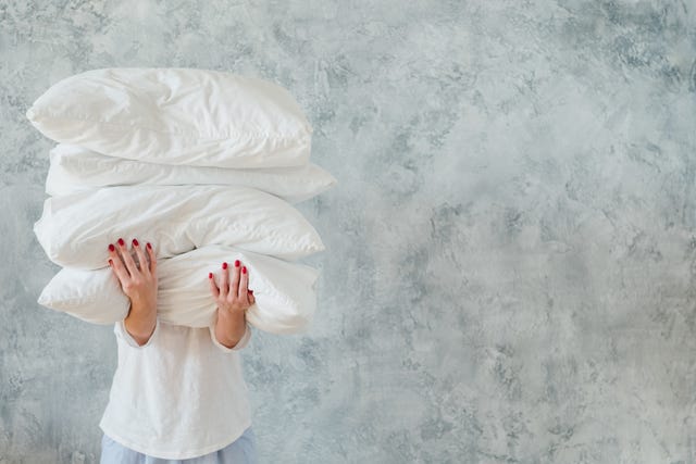 woman hold pile white pillows bedding sleeping