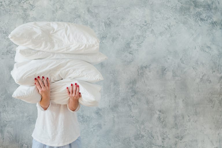 a woman holding four pillows