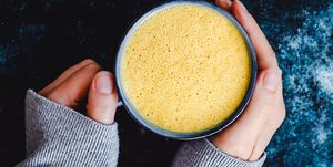 woman holding a cup of turmeric milk