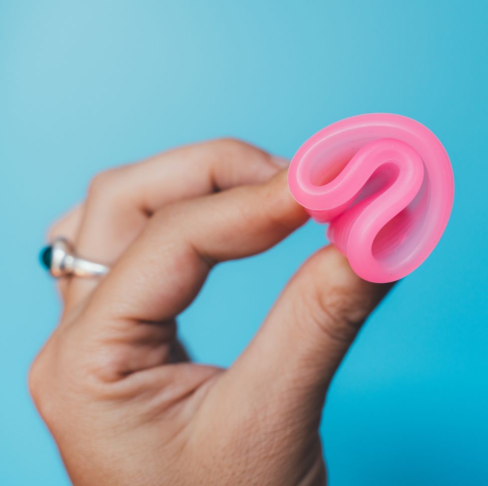 Woman holding a pink menstrual cup on blue background