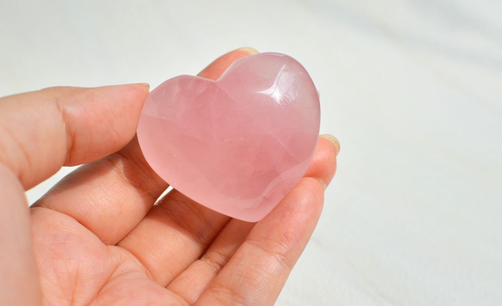 woman holding a rose quartz crystal heart