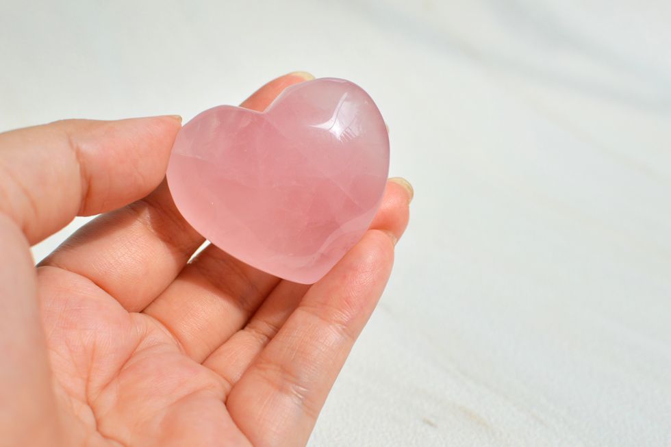 woman holding a rose quartz crystal heart