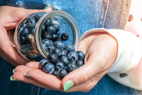 good carbs to eat, woman holding bowl with fresh blueberries harvesting concept female hands collecting berries