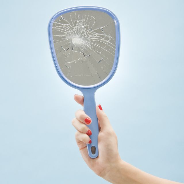 woman holding broken mirror